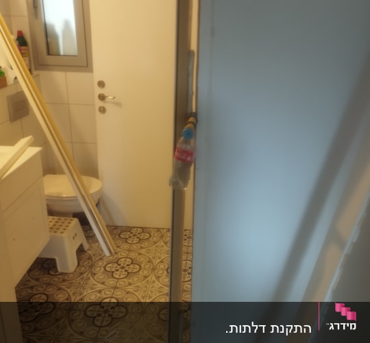 דלת לבנה בחדר אמבטיה עם רצפה מעוצבת